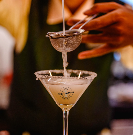 The Crafted Pour cocktail being strained into a glass